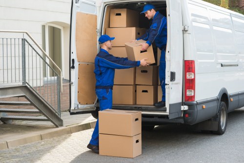 Local removals crew transporting furniture through a residential street in Morden